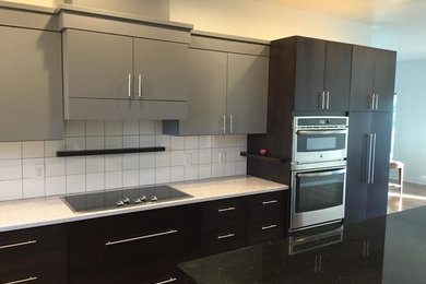Inspiration for a mid-sized transitional single-wall eat-in kitchen remodel in Cedar Rapids with flat-panel cabinets, gray cabinets, quartz countertops, white backsplash, ceramic backsplash, stainless steel appliances and an island