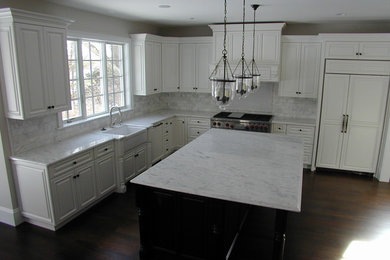 Inspiration for a large timeless l-shaped dark wood floor and brown floor eat-in kitchen remodel in Boston with a farmhouse sink, raised-panel cabinets, white cabinets, marble countertops, gray backsplash, marble backsplash, paneled appliances and an island