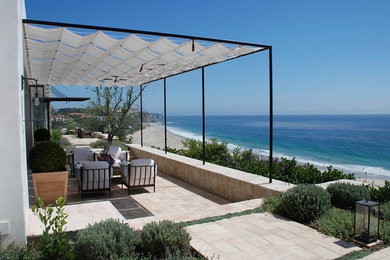 Photo of an expansive mediterranean backyard patio in Orange County with a fire feature, gravel and a pergola.