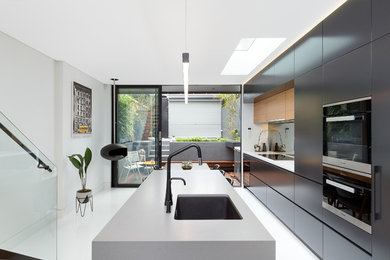 Inspiration for a mid-sized modern galley eat-in kitchen in Sydney with an undermount sink, black splashback, glass sheet splashback, stainless steel appliances and with island.
