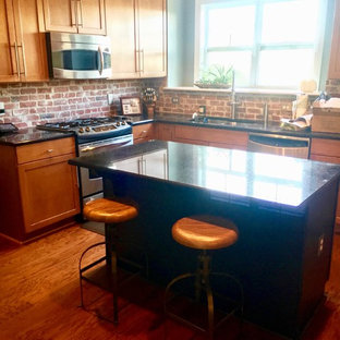 Mid-sized industrial eat-in kitchen photos - Mid-sized urban l-shaped medium tone wood floor and brown floor eat-in kitchen photo in Charlotte with an undermount sink, shaker cabinets, medium tone wood cabinets, red backsplash, brick backsplash, stainless steel appliances and an island
