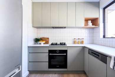 シドニーにある小さなモダンスタイルのおしゃれなキッチン (アンダーカウンターシンク、フラットパネル扉のキャビネット、緑のキャビネット、クオーツストーンカウンター、白いキッチンパネル、磁器タイルのキッチンパネル、シルバーの調理設備、淡色無垢フローリング、アイランドなし、白いキッチンカウンター、板張り天井) の写真