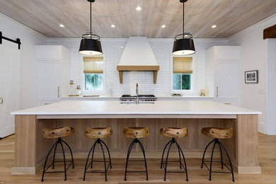 Open concept kitchen - large country single-wall medium tone wood floor and brown floor open concept kitchen idea in Charleston with an undermount sink, shaker cabinets, white cabinets, quartzite countertops, white backsplash, subway tile backsplash, paneled appliances, an island and white countertops