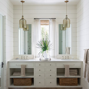 Maritimes Badezimmer En Suite mit offenen Schränken, grauen Schränken, weißer Wandfarbe, hellem Holzboden, Unterbauwaschbecken, weißer Waschtischplatte und Doppelwaschbecken in Charleston