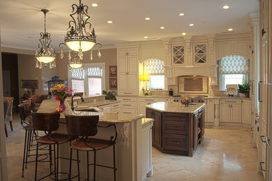 Inspiration for a large timeless l-shaped limestone floor and beige floor enclosed kitchen remodel in Huntington with an undermount sink, recessed-panel cabinets, white cabinets, granite countertops, beige backsplash, stone tile backsplash, paneled appliances and an island
