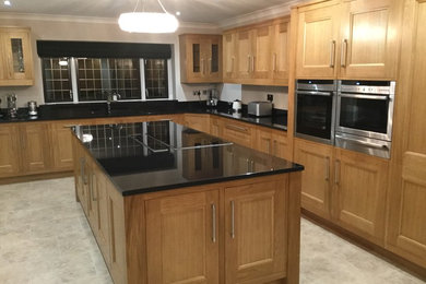 Large classic open plan kitchen in Essex with a submerged sink, beaded cabinets, medium wood cabinets, granite worktops and multiple islands.