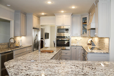 Photo of a large transitional u-shaped separate kitchen in Dallas with an undermount sink, shaker cabinets, grey cabinets, granite benchtops, beige splashback, stone tile splashback, stainless steel appliances, porcelain floors and with island.