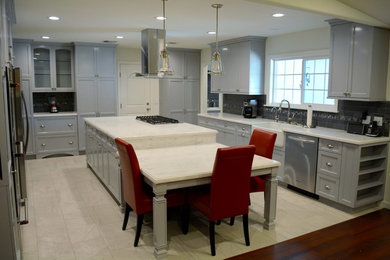 Transitional porcelain tile kitchen photo in Los Angeles with a farmhouse sink, recessed-panel cabinets, gray cabinets, quartzite countertops, glass tile backsplash and stainless steel appliances