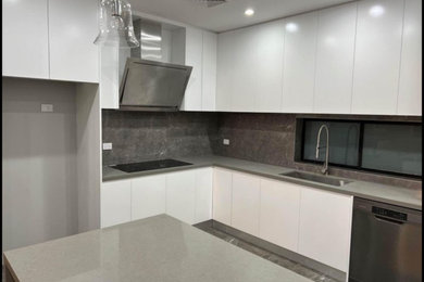 Photo of a large modern l-shaped open plan kitchen in Sydney with a single-bowl sink, quartzite benchtops, grey splashback, porcelain splashback, stainless steel appliances, porcelain floors, with island, grey floor and grey benchtop.