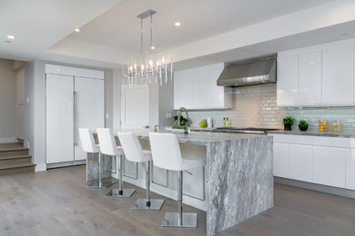 This is an example of a large modern l-shaped separate kitchen in San Diego with an undermount sink, flat-panel cabinets, white cabinets, marble benchtops, grey splashback, subway tile splashback, stainless steel appliances, light hardwood floors, with island and beige floor.