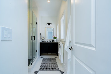 Идея дизайна: ванная комната среднего размера в стиле неоклассика (современная классика) с плоскими фасадами, черными фасадами, угловым душем, белой плиткой, керамогранитной плиткой, белыми стенами, полом из керамогранита, душевой кабиной, врезной раковиной, столешницей из искусственного кварца, белым полом, душем с распашными дверями, белой столешницей, тумбой под одну раковину и встроенной тумбой