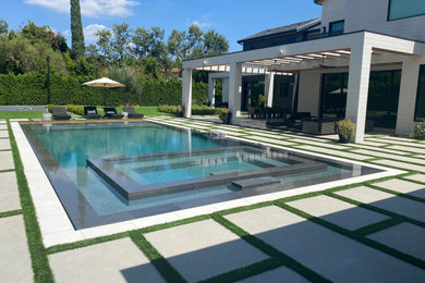 Large minimalist backyard concrete paver and rectangular infinity and privacy pool photo in Los Angeles