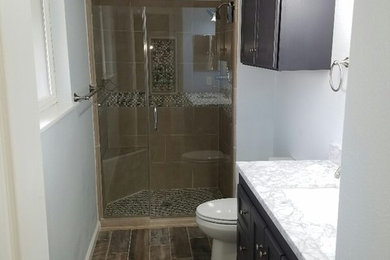Example of a mid-sized transitional beige tile and porcelain tile porcelain tile and beige floor alcove shower design in Other with shaker cabinets, brown cabinets, a two-piece toilet, white walls, an undermount sink, granite countertops and a hinged shower door
