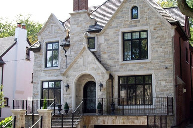 This is an example of a mid-sized two-storey grey house exterior in Toronto with stone veneer, a hip roof and a shingle roof.