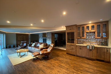 Inspiration for a mid-sized rustic open concept dark wood floor and brown floor family room remodel in Other with beige walls, a two-sided fireplace, a stone fireplace and a media wall