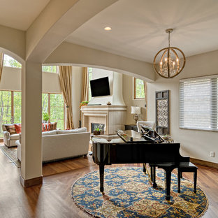 Großes Mediterranes Wohnzimmer im Loft-Stil mit beiger Wandfarbe, braunem Holzboden, Kamin, Kaminsims aus Stein, Wand-TV und braunem Boden in Minneapolis
