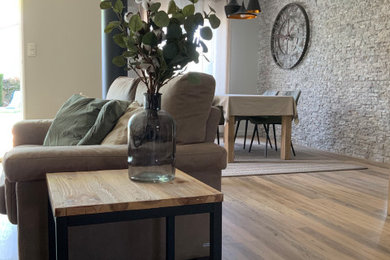 Exemple d'un salon tendance de taille moyenne et ouvert avec un mur blanc, un sol en vinyl, un sol marron et un mur en parement de brique.