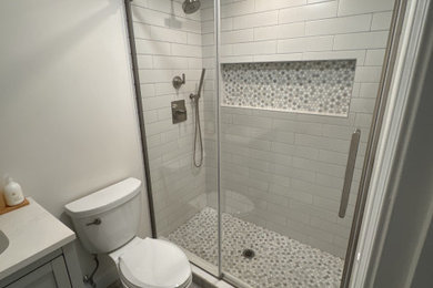Inspiration for a small modern white tile and ceramic tile ceramic tile, gray floor and single-sink bathroom remodel in Boston with shaker cabinets, gray cabinets, a two-piece toilet, gray walls, an integrated sink, quartz countertops, white countertops, a niche and a freestanding vanity