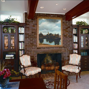 This is an example of a mid-sized traditional home office in DC Metro with a library, beige walls, porcelain floors, a standard fireplace, a brick fireplace surround, a freestanding desk and beige floor.