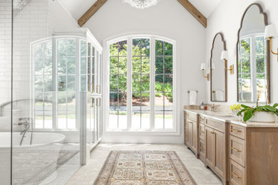 Bathroom - large transitional master white tile and subway tile ceramic tile, gray floor, double-sink and vaulted ceiling bathroom idea in Atlanta with shaker cabinets, light wood cabinets, white walls, an undermount sink, quartz countertops, a hinged shower door, beige countertops and a built-in vanity