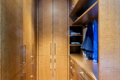 This is an example of a contemporary gender-neutral walk-in wardrobe in Ottawa with flat-panel cabinets, medium wood cabinets and beige floor.