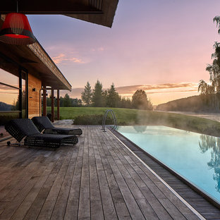 Bild på en mellanstor funkis rektangulär ovanmarkspool framför huset, med en fontän