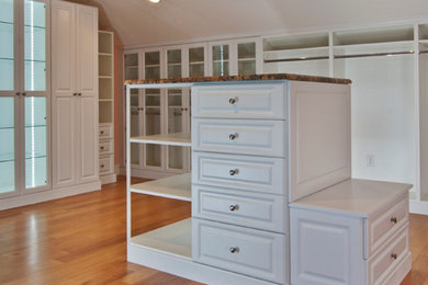 Example of a large classic gender-neutral medium tone wood floor walk-in closet design in Orlando with raised-panel cabinets and white cabinets