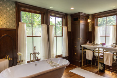 Large ornate master dark wood floor, brown floor, double-sink and wainscoting bathroom photo in Cincinnati with furniture-like cabinets, brown cabinets, a one-piece toilet, multicolored walls, a pedestal sink, granite countertops, a hinged shower door, white countertops and a freestanding vanity