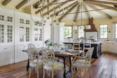 Large farmhouse dark wood floor, brown floor and exposed beam eat-in kitchen photo in Other with a farmhouse sink, white cabinets, marble countertops, an island and white countertops