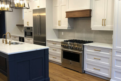 Huge transitional single-wall medium tone wood floor and brown floor open concept kitchen photo in Toronto with an undermount sink, shaker cabinets, white cabinets, quartz countertops, gray backsplash, subway tile backsplash, stainless steel appliances, an island and white countertops