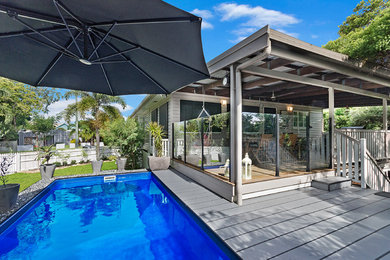Beach style backyard rectangular pool in Townsville with decking.