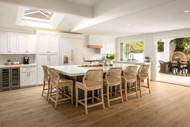 Large beach style eat-in kitchen photo in Orange County with a drop-in sink, shaker cabinets, white cabinets, quartzite countertops, white backsplash, paneled appliances, an island and white countertops