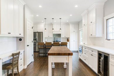 Inspiration for a mid-sized transitional dark wood floor and brown floor eat-in kitchen remodel in Chicago with an undermount sink, recessed-panel cabinets, white cabinets, quartzite countertops, white backsplash, subway tile backsplash, stainless steel appliances, two islands and white countertops