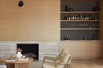 Imagen de salón con barra de bar abierto minimalista grande sin televisor con paredes blancas, suelo de madera clara, todas las chimeneas, marco de chimenea de piedra y suelo beige