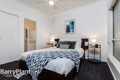 Modern master bedroom in Melbourne with white walls and carpet.