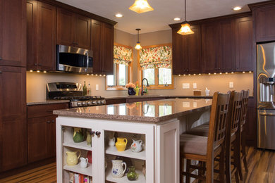 Large traditional l-shaped open plan kitchen in Other with an undermount sink, recessed-panel cabinets, medium wood cabinets, stainless steel appliances, medium hardwood floors, with island and brown floor.