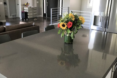 Mid-sized transitional l-shaped light wood floor and gray floor eat-in kitchen photo in Other with an undermount sink, recessed-panel cabinets, white cabinets, quartz countertops, gray backsplash, ceramic backsplash, stainless steel appliances and an island