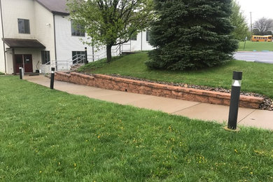 This is an example of a small traditional full sun side yard concrete paver retaining wall landscape in Other for fall.