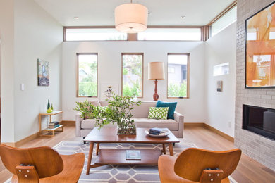 Example of a trendy medium tone wood floor living room design in Los Angeles with white walls and a ribbon fireplace