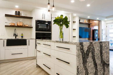 Open concept kitchen - large modern l-shaped light wood floor and beige floor open concept kitchen idea in Other with a farmhouse sink, flat-panel cabinets, white cabinets, quartz countertops, white backsplash, black appliances and an island