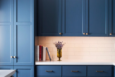 Example of a mid-sized transitional porcelain tile and gray floor kitchen design in San Francisco with an undermount sink, recessed-panel cabinets, blue cabinets, quartzite countertops, white backsplash, subway tile backsplash, stainless steel appliances and white countertops