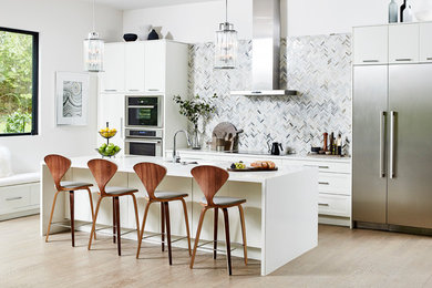 Inspiration for a large contemporary galley kitchen in Toronto with recessed-panel cabinets, white cabinets, grey splashback, mosaic tile splashback, stainless steel appliances, light hardwood floors, with island, beige floor and white benchtop.