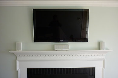 Example of a living room design in Burlington with green walls, a standard fireplace, a stone fireplace and a wall-mounted tv