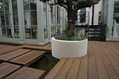 Réalisation d'un petit jardin arrière design avec un bassin, une exposition partiellement ombragée et une terrasse en bois.