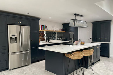 Imagen de cocina comedor lineal actual grande con armarios estilo shaker, puertas de armario grises, encimera de acrílico y una isla