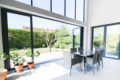 Expansive contemporary open plan dining in London with white walls, ceramic floors and grey floor.