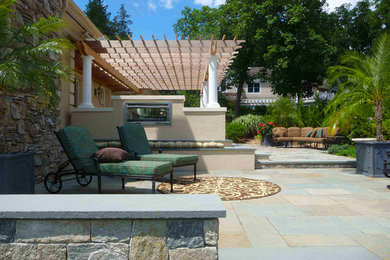 Inspiration for a mid-sized traditional backyard patio in Bridgeport with a fire feature, natural stone pavers and a pergola.