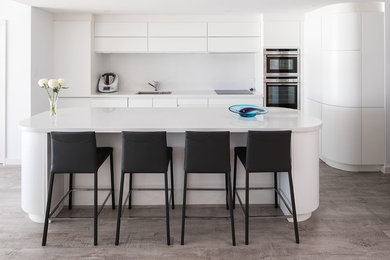 Design ideas for a contemporary kitchen in Perth with flat-panel cabinets, white cabinets, white splashback, stainless steel appliances, with island and a double-bowl sink.
