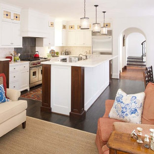 Imagen de cocina en L, ecléctica, abierta, con armarios tipo vitrina, electrodomésticos de acero inoxidable, fregadero sobremueble, encimera de mármol, salpicadero de azulejos de piedra, suelo de madera oscura y una isla