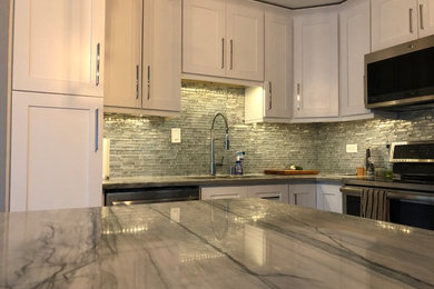 Eat-in kitchen - mid-sized contemporary l-shaped vinyl floor and brown floor eat-in kitchen idea in Chicago with an undermount sink, shaker cabinets, white cabinets, quartzite countertops, gray backsplash, mosaic tile backsplash, stainless steel appliances, an island and gray countertops